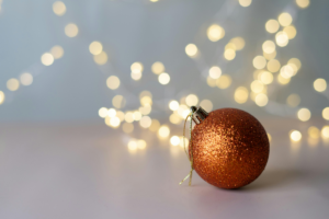 Kauniit, luonnonvalkoiset jouluvalot pronssin värisen joulupallon takana